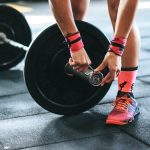 person locking gym plates on barbell